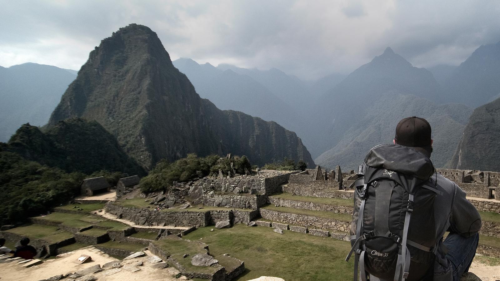Sunlight hits the sacred city of Machu Picchu, brightening all of the lush, green grass that surrounds the ruins on a bright morning near Cusco, Peru