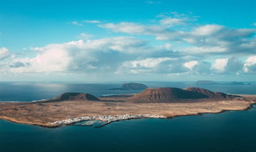 The island of Lanzarote, the Canary Islands, surrounded by ocean with blue sky and clouds in the background.