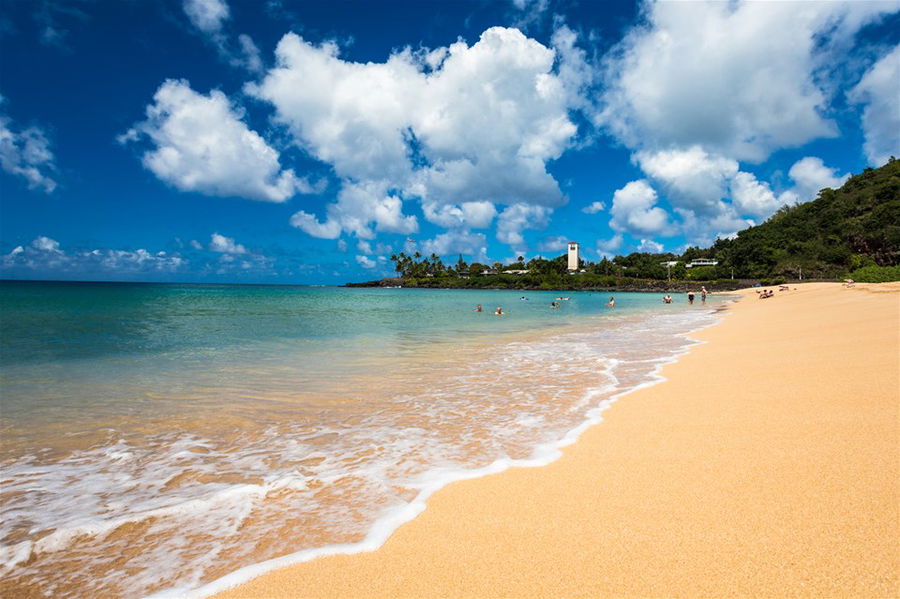 The golden sand beach of Waimea Bay on a bright, sunny day