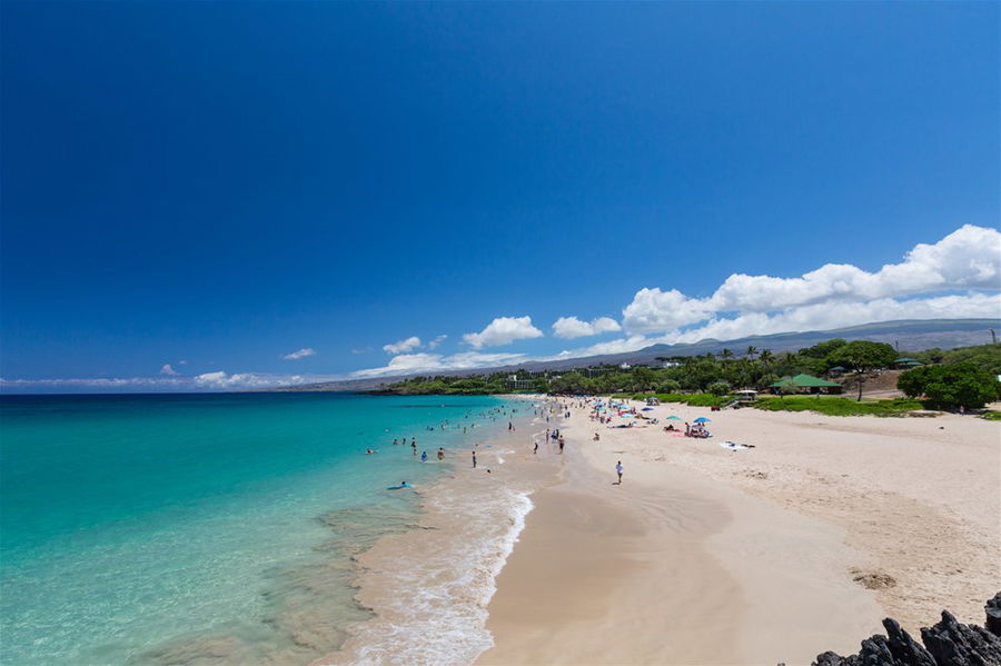 A wide stretch of beach lapped by blue, crystal clear waters