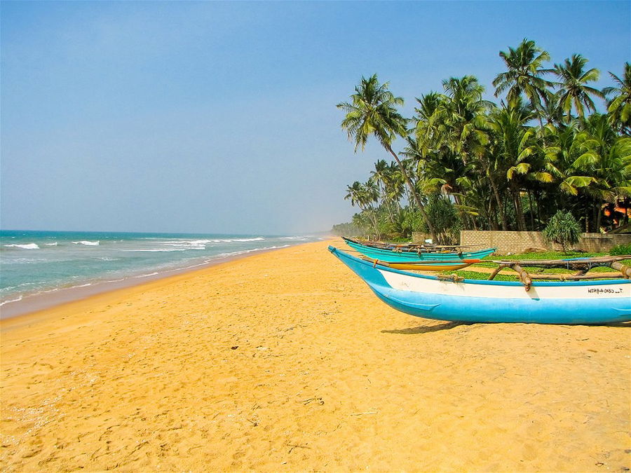 Fishing boats sit on the golden sands of Kalutara Beach in Sri Lanka