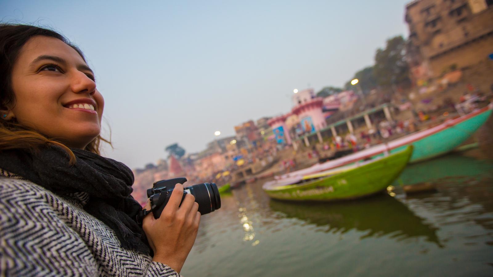 People throwing handfuls of seed into the air as flocks of gulls swarm the boats on the Ganges in Varanasi, India, at sunrise