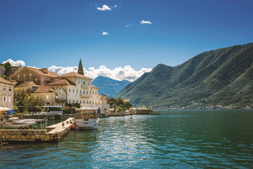 A small harbour near old stone buildings of Kotor in Montenegro with green hills in the distance
