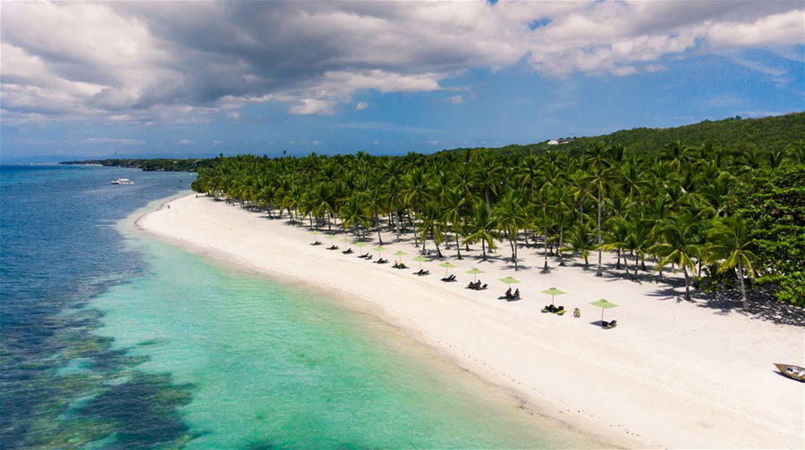 An aerial view of a long white sand beach and clear turquoise waters in the Philippines