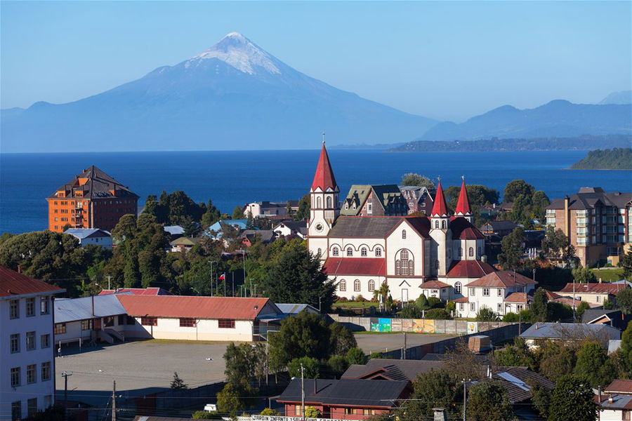 A view across the rooftops of the town of Puerto Varas in Chile, to the ocean and mountains in the distance