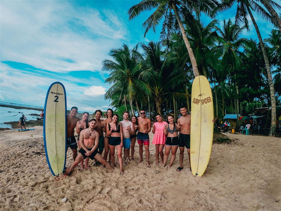 A group of young surfers stand on a beach in the Philippines