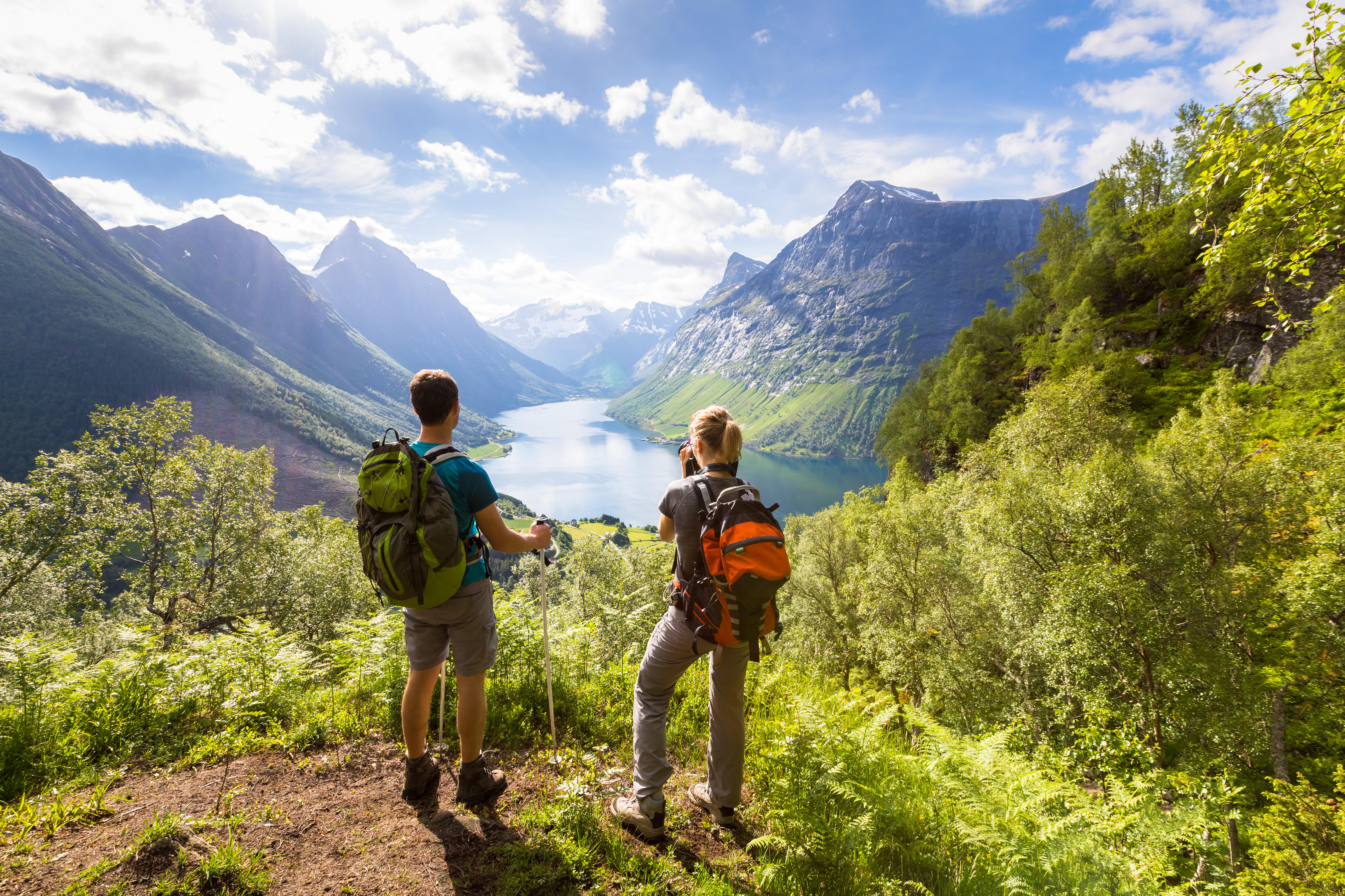 Two hikers at viewpoint in the mountains enjoying beautiful view of the valley, Norway