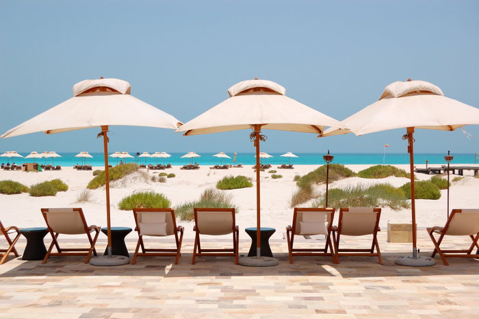 Sunbeds and umbrellas at the Beach of luxury hotel, Abu Dhabi, UAE