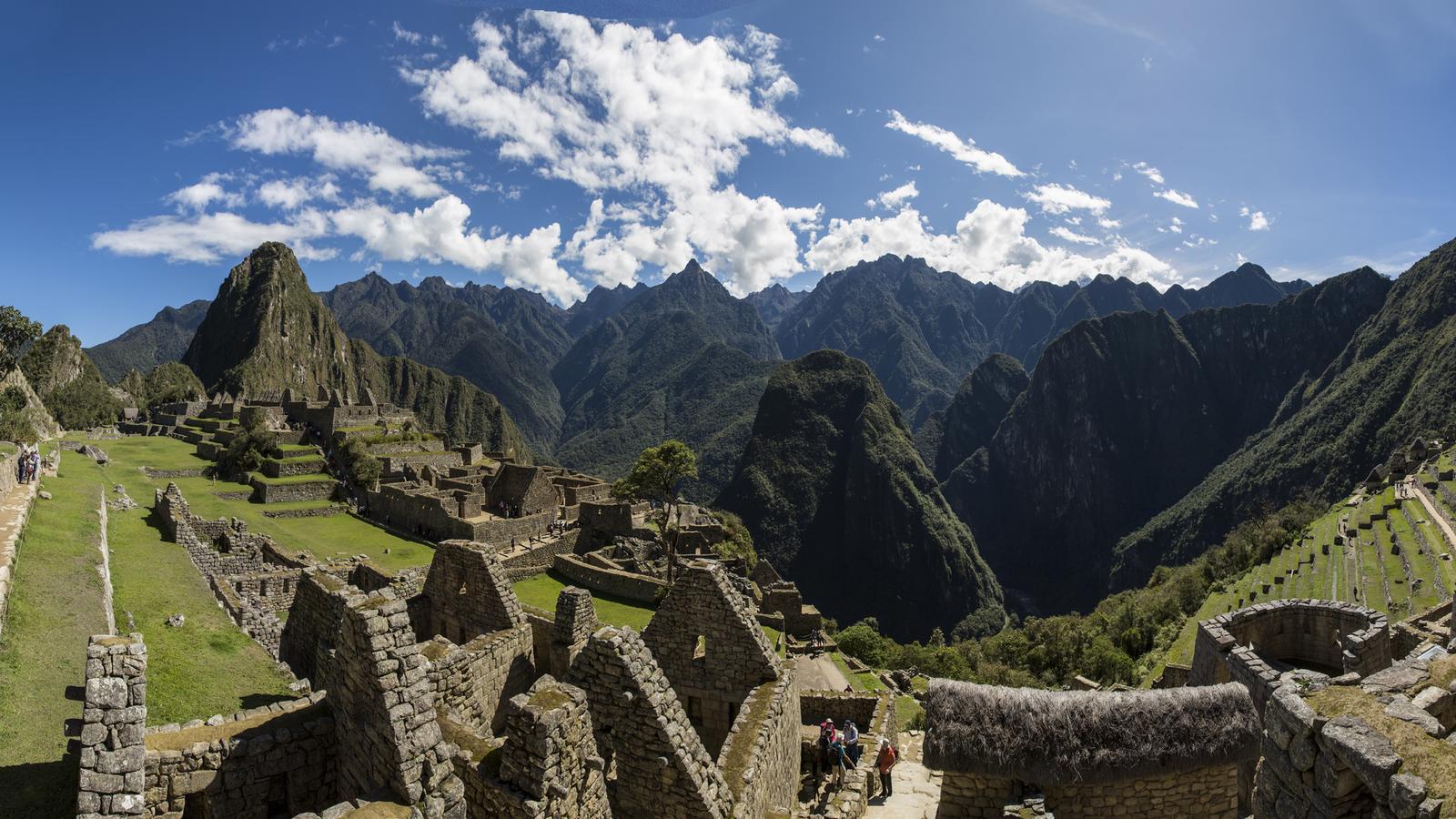 A tourist taking a photograph of the terraces of the Sacred Valley on a sunny day in Peru