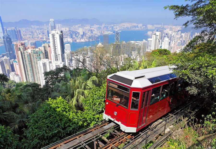 The red Peak Tram in Hong Kong going up a mountain with skyscrapers in the background