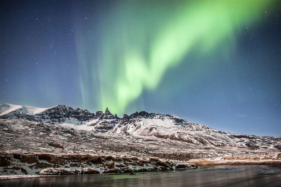 The northern lights over a mountain in iceland