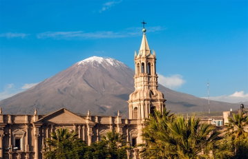 The pointy spire of the Basilica Cathedral of Arequipa with Volcano El Misti rising high above the city behind it