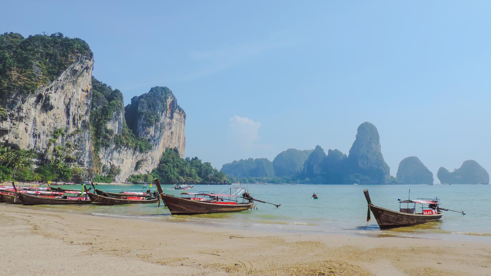 People floating on inflatables in the gently lapping waters around Khao Sok National Park in Thailand with mountain peaks rising in the distance