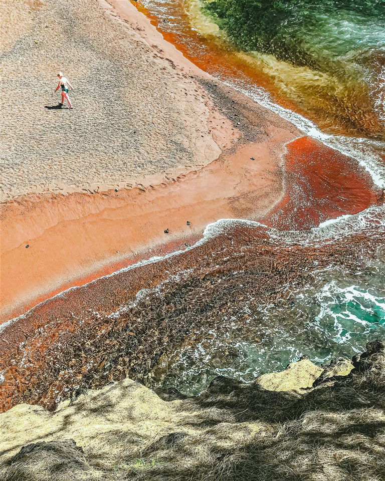 An aerial view of a unique red sand beach in Hawaii