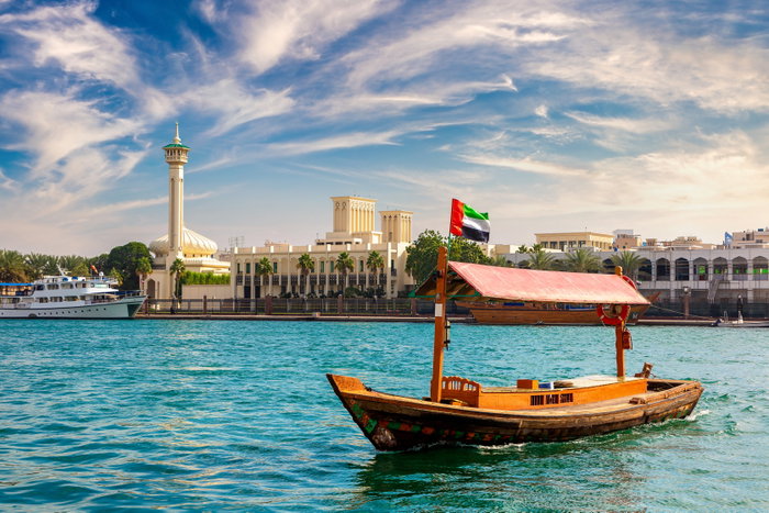 Abra - old traditional wooden boat and Al Farooq Mosque on the bay Creek in Dubai, United Arab Emirates