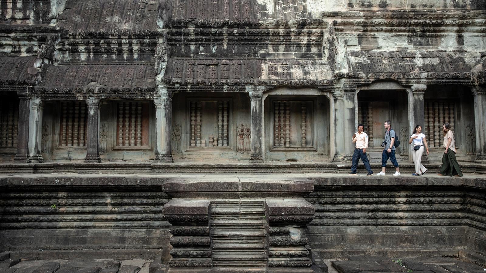 A female guide leads young travellers around the temples of Wat Pho, Bangkok