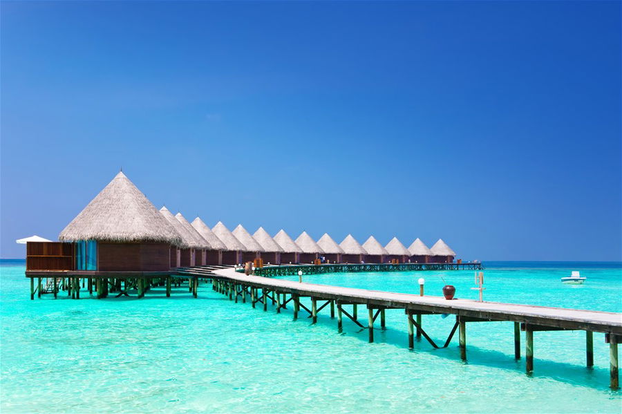 A long jetty leads to a row of overwater villas in the Maldives