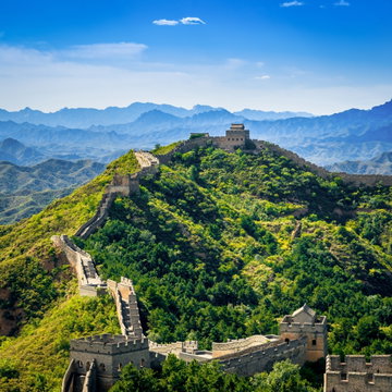 The stones of the serpentine Great Wall of China burst above the forested hills on which it is built. Near Beijing, China