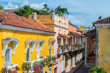 Brightly coloured colonial buildings and balconies laden with flowers stand on a narrow street in the historic centre of Cartagena, Colombia