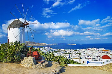 Whitewashed buildings along the bay frame the blue sea in Mykonos, Greece.