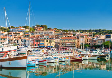 Colourful buildings perched on the edge of the glistening harbour, full with yachts & sail boats, French Riviera.
