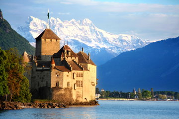 View of Chillon Castle from across Lake Geneva with snow covered mountain in the background, Montreux Switzerland
