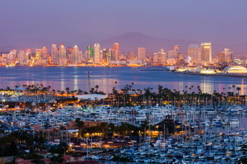 The evening sun illuminating the impressive downtown skyline of San Diego, California, USA, overlooked by the bustling harbour across the tranquil water