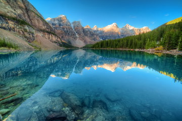 Striking blue sky and pristine blue water of Lake Moraine reflect the towering snow-capped mountains of the valley of the ten peaks in Banff National Park, Canada. 