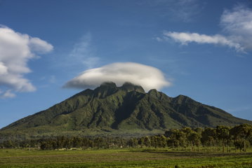 Clouds roll over the green slopes and rugged, towering peaks at Volcanoes National Park, Rwanda