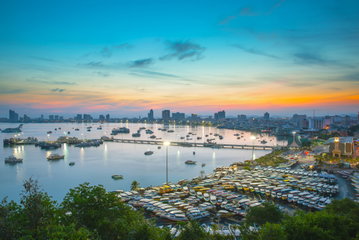 A busy aerial view of Pattaya Thailand with a beautiful orange sun setting over the hotels and boats lining the shore