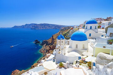 A stunning view of Greece from atop the whitewashed domes of Santorini, down to the deep blue Aegean Sea below