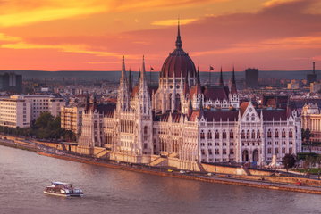 The gothic spires of the Budapest Parliament, Hungary cuts an impressive figure against an orange sunset sky, Central Europe