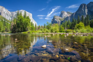An array of lush green forest and towering rocky formations reflect off the clears waters in Yosemite Valley on a beautiful summers’ day, Yosemite National Park, California, USA 