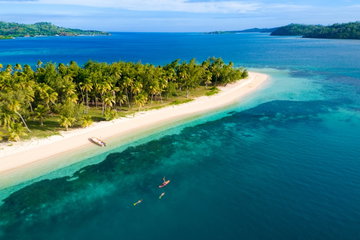 Secluded Castaway Island in Fiji amid the turquoise sea, dotted with coral reefs