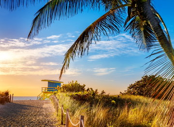 Sandy path leads down to a beach hut overlooking the calm ocean at sunset in Florida, USA