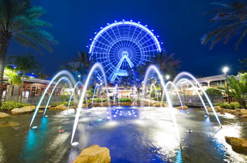 Looking up over a water fountain to the lit up Orlando Eye that stands proudly on International drive on a warm evening in Orlando, Florida, USA