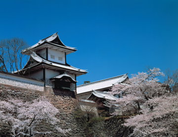 The white roof of Hashizume-mon Gate at Kanazawa Castle Park, Japan, against a peiricng blue sky.