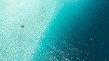 A catamaran floats on the vast, tropical, crystal clear water of the Maldives.