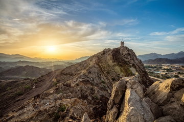 Mist floats over the Ajman Masfout mountains as the sun rises in the distance