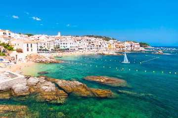 Crystal clear waters, lapping up on small, golden sand coves where sunbathers bask in the sun, surrounded by white washed buildings, stretching all around the coast. Calella de Palafrugell, Costa Brava