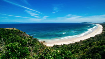 A stretch of white powdery sand leading towards the turquoise sea, surrounded by rich, dense forest, New South Wales, Australia