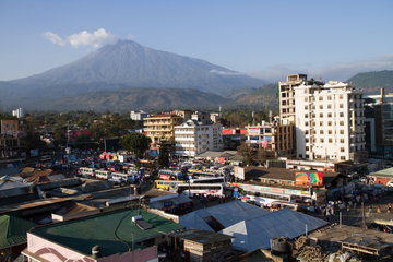 Aerial view of busy Arusha city, with lots of buildings, cars and buses, with Mount Meru in the background, Tanzania