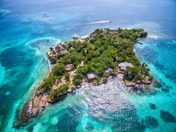 Aerial view of lush green Isla del Pirata surrounded by reef and azure blue sea at Rosario Islands off the coast of Cartagena, Colombia