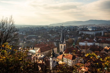 Aerial view of Ljubljana with pretty buildings with terracotta roofs and a church with a grand black steeple, Slovenia