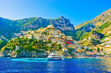 The colourful buildings of the city of Amalfi cling to the cliff side high above the turquoise Mediterranean Sea, the Amalfi Coast, Italy