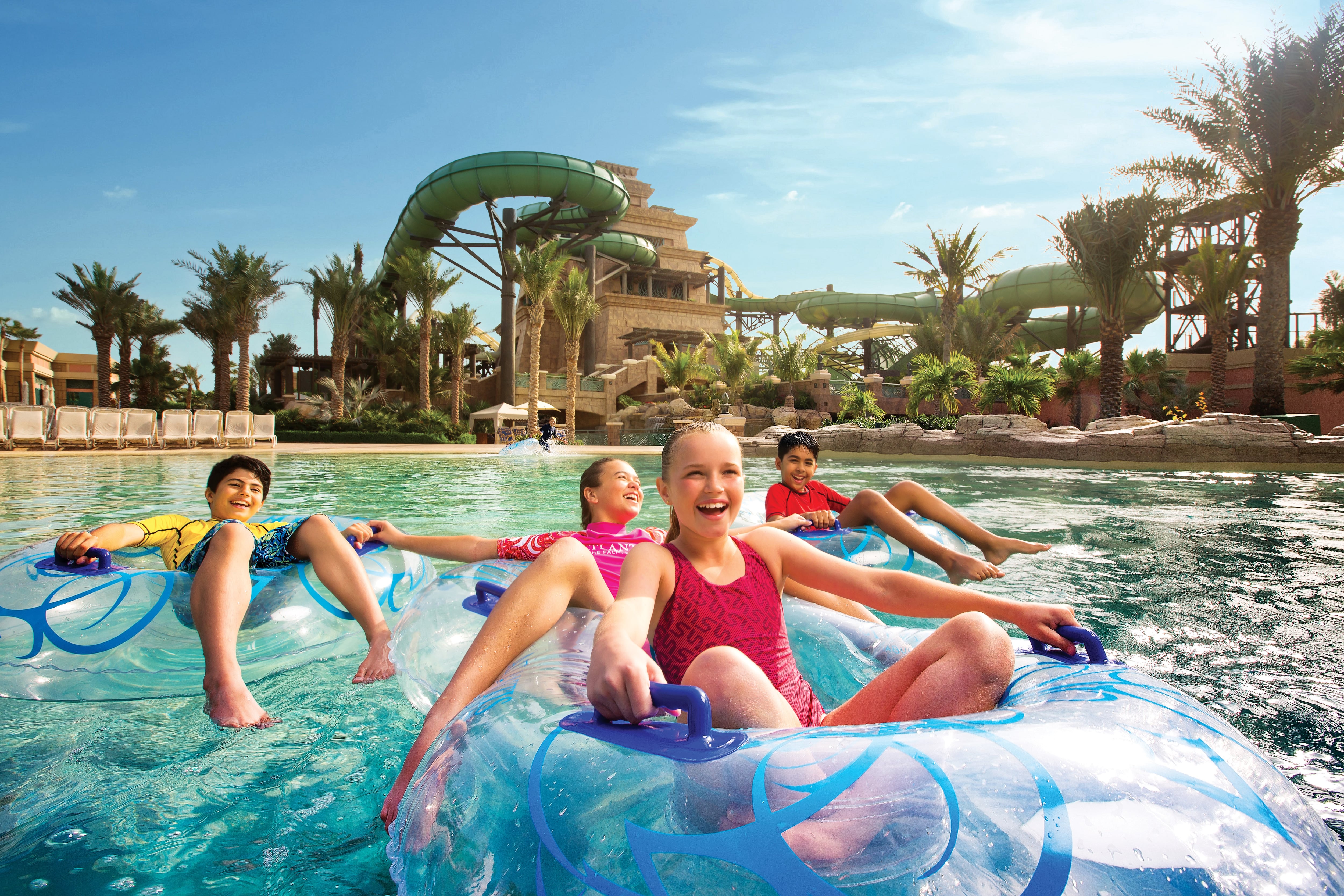 Children laughing in giant inflatables with exciting waterslides in the background at Atlantis Aquaventure, Dubai