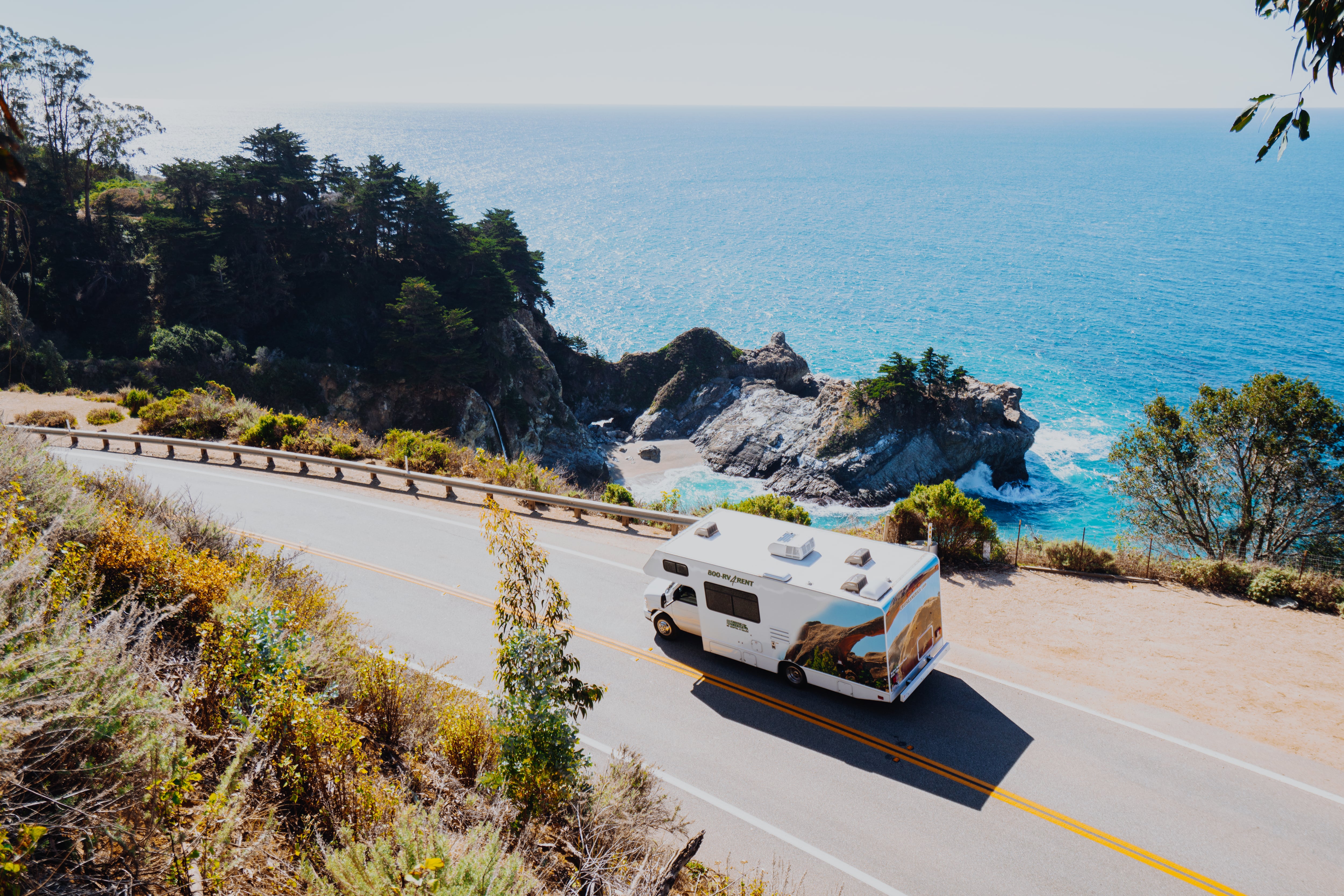 A Cruise America campervan travels along the coastal Highway 101 where dramatic rocks emerge from the choppy turquoise waters