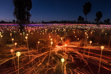 A wide angle shot of thousands of colourful glass spheres coming to life in the night sky in the Australian outback, Ayers Rock