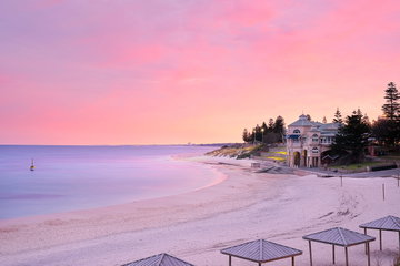 After sun set at Cottelsoe beach with a calm sea and white sandy beach below a hazy pink sky, Perth, Australia