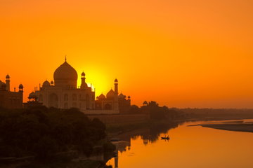 Taj Mahal India with beautiful orange sunset in background with Lake Yamuna in the foreground
